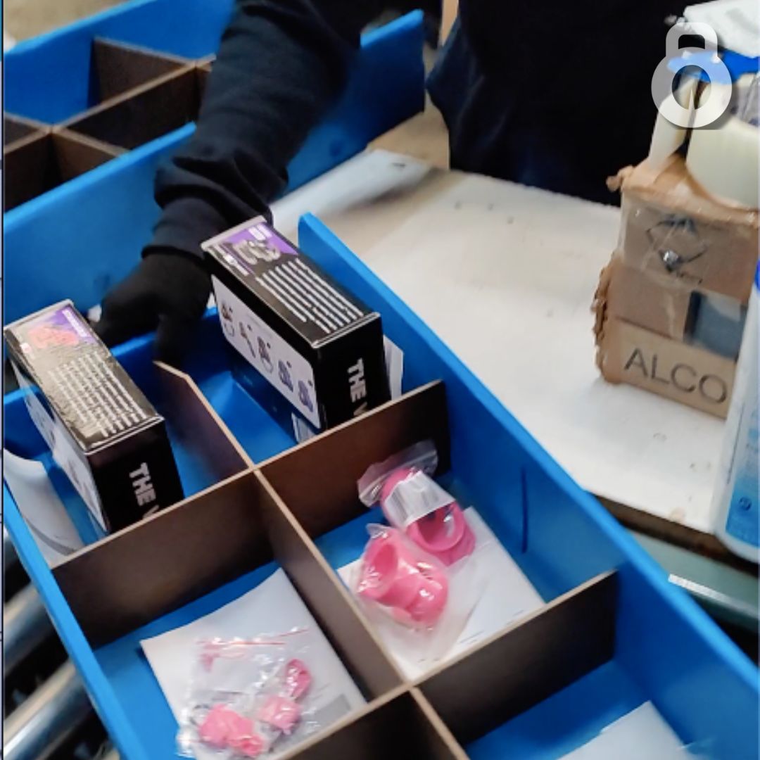 tray of multiple Vice chastity products being pushed onto conveyor belt.